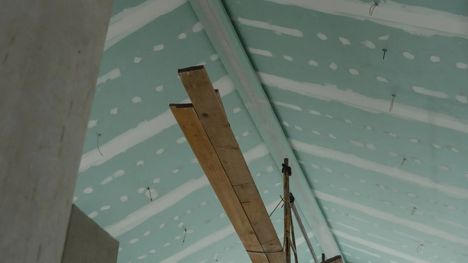 Board being fixed to ceiling framing with a timber prop holding it up